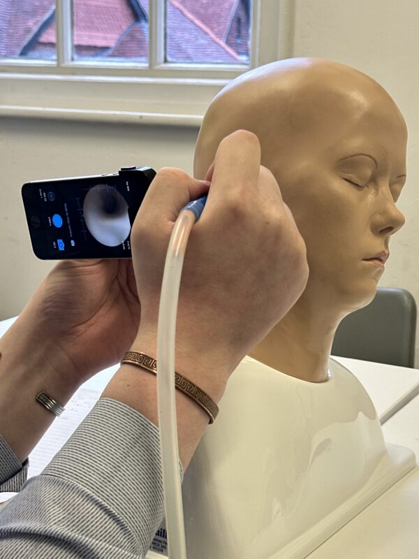 Student being trained for ear wax removal via microsuction on a mannequin head